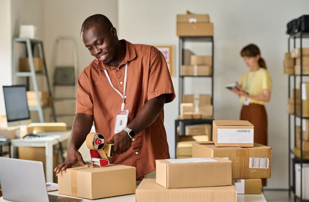 Un préparateur scelle des cartons d’expédition dans un entrepôt.